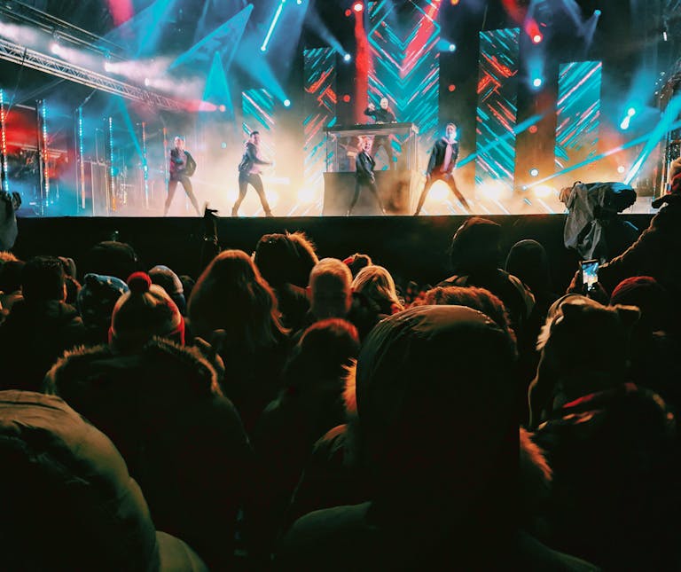 Energetic concert crowd enjoying a nighttime performance in Helsinki with vibrant lights and performers.